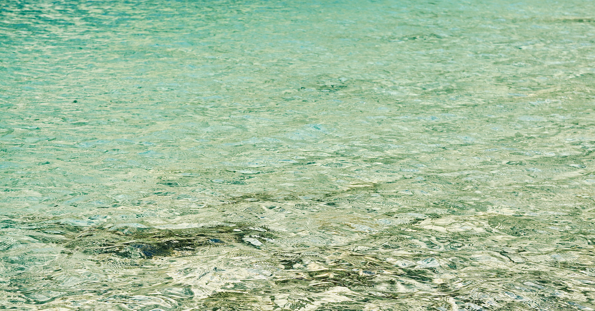 A serene image of tranquil, crystal clear turquoise water surface with gentle ripples.